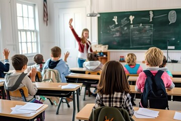 A schoolboy raises his hand up sitting at a desk in the background of a classroom with other students