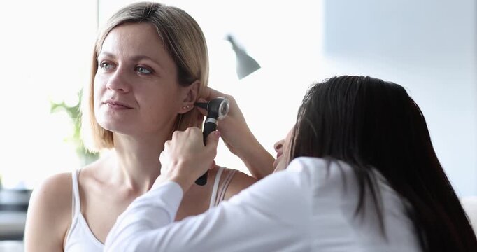 ENT conducts medical examination of patient ear with otoscope. Hearing problem in adults concept