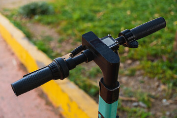 Close up on the handlebars of a scooter, in a public park