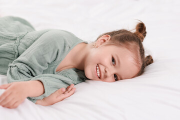 Portrait of happy little girl on bed