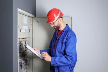 Technician worker with clipboard inspecting electricity meter