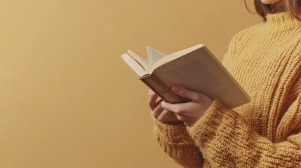 Fototapeta na wymiar A left-handed person holding a book open with their left hand, reading in a cozy setting. The background is a simple, warm-toned space with ample copy space around the book and hand.