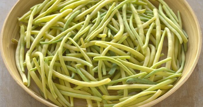 Freshly harvested Golden Teepee variety yellow string beans on a bamboo tray.  Table spin.