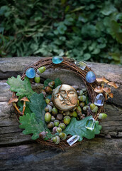 moon amulet, minerals, acorns, oak leaves, mushrooms on tree trunk, natural background. forest...