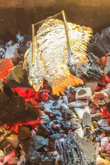 Freshly caught fish are grilling over glowing embers. Rustic, outdoor setup enhances adventure and charm of this picnic feast. Wild feasting. Vertical format