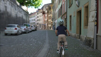 Boy cycling through scenic cobblestone street lined, historic buildings, emphasizing adventure and exploration in a quaint urban setting, ideal for travel