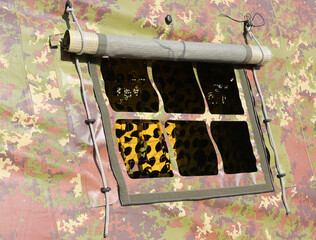 small window detail of a military tent with camouflage fabric set up in a training camp during war