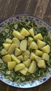 South Croatian Blitva dish. The dish is made with boiled potatoes, swiss chard, garlic, and olive oil.  Table spin, copy space, vertical video.