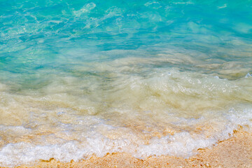turquoise blue sea crystal water on coast with rising tide of small pounding waves.