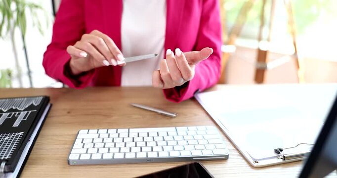 Woman secretary doing manicure at workplace in office closeup 4k movie slow motion. Idleness at work concept