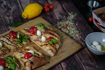 Delicious homemade Italian pizza with fresh basil, cherry tomatoes, and mozzarela. Dark wood background. High quality photo