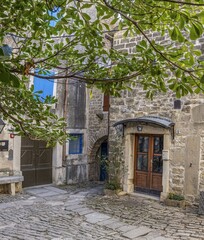 an alley with a stone walkway and a wooden door and blue shutters