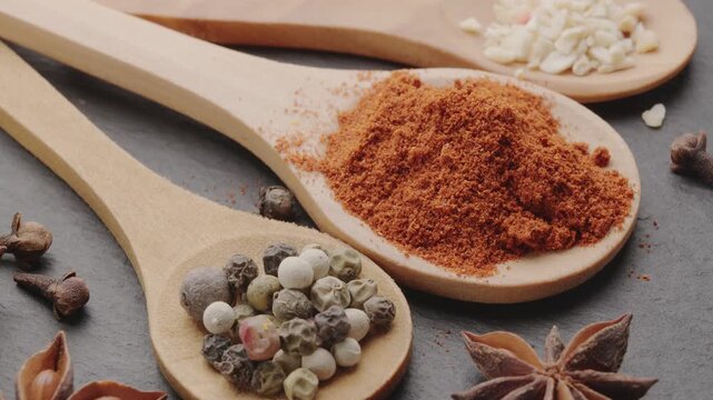 Various types of spices on wooden spoons slowly move along the frame, a great food background for your projects.