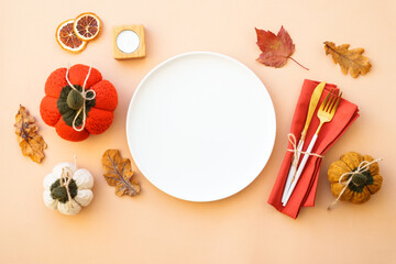 Autumn table setting. Cozy fall decorations, white plate and golden cutlery on color background. Flat lay.