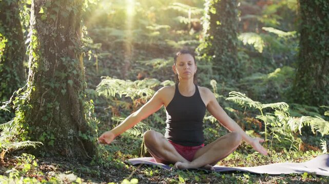 Woman is practicing yoga in nature. Seated gentle easy pose for relief.