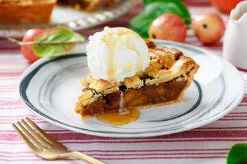 Piece of an apple pie with ice cream scoop and sugar syrup on a plate