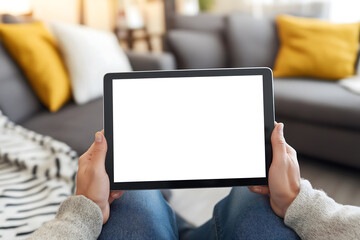 A person holding a blank digital tablet with both hands, ready for mock up, against a comfortable home setting
