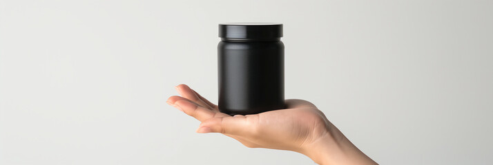 Hand Holding Black Supplement Bottle