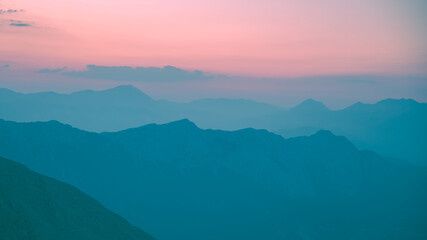Fototapeta premium Silhouettes of mountains in a beautiful gentle haze, mountains at sunset or sunrise, natural background