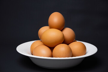 White plate with arrangement of raw chicken eggs. Raw chicken eggs for cooking purposes.