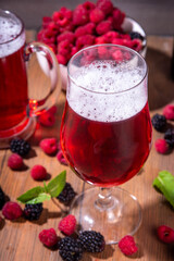 Tasty sweet fruit berry craft beer ale or Cider,  cold  berry beer shandy cocktail on wooden table with fresh raspberry and blackberry
