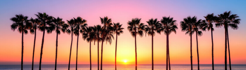 Obraz premium Scenic sunset view with palm trees silhouetted against a colorful sky, creating a tranquil and picturesque landscape.