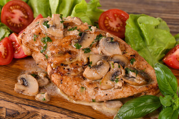 Chicken breast with mushroom sauce and vegetables on a wooden plate
