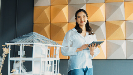 Beautiful project manager using tablet check house model. Portrait of architect engineer inspect building construction by using data analysis from tablet. Business construction concept. Manipulator.