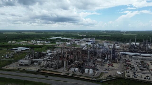 Flyover highway near large oil refinery complex plant with gas flare, crude oil distillation unit, storage tanks, utility systems, pipelines in rural agriculture agro-town San Antonio, Texas