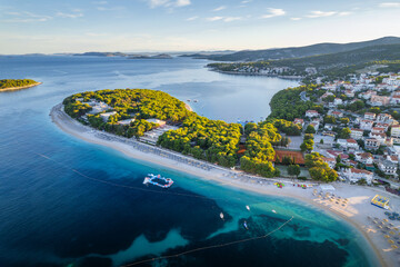 Aerial view of the peninsula surrounded by a wonderful beach with azure water in Primosten, Croatia.