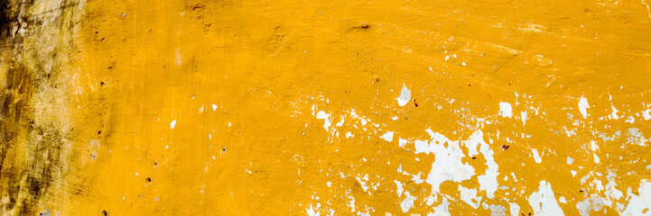 A close-up of a weathered yellow wall with peeling paint suggesting neglect and urban decay