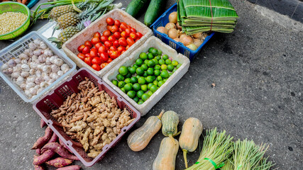 A vibrant display of fresh produce including tomatoes, ginger, and lime at an Asian street market, symbolizing local agriculture