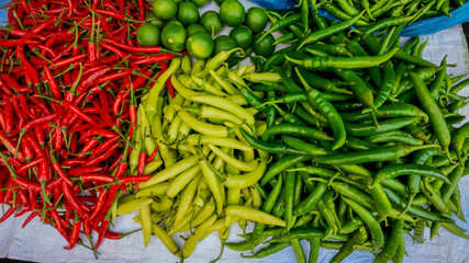 Assorted colorful chillies and green limes for sale at a local market, highlighting fresh produce and cooking essentials