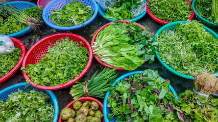 Fresh green vegetables in colorful baskets on display at a local Asian market, promoting healthy eating and sustainable living