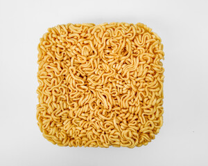 Uncooked square block of instant ramen noodles isolated on white background, representing quick meals and convenience cooking