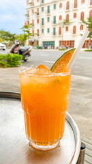 Refreshing tropical orange drink with ice cubes and a slice of lime in a glass, perfect for summer relaxation