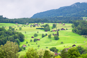Obraz premium Beautiful view of little houses and wooden cottages on a green mountain meadow near the village of Sarnen in central Switzerland