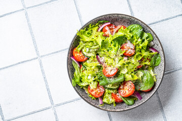 Green vegetable salad with fresh leaves. Top view on white tile background.