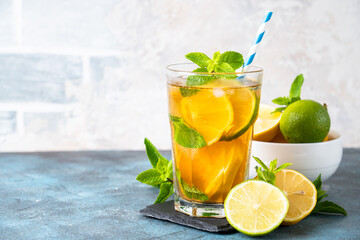 Iced tea with ingredients. Black tea with lemon, lime, mint and ice. Cold lemonade, summer drink at kitchen table.