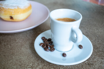 Close-up of berliner cake on a white plate and a cup of espresso