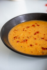 Adding spices and pepper to lentil soup with vegetables