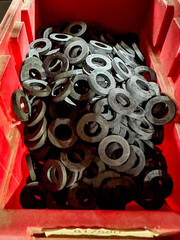 Round black rubber gaskets in a red storage container