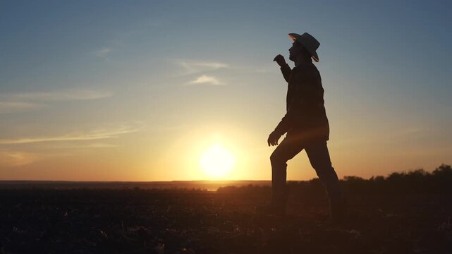 Agriculture. Silhouette of a farmer walking in the field. Landscape fresh harvest concept. Farmer walks through the soils. Silhouette of farmer walking through the field lifestyle in soild soil.