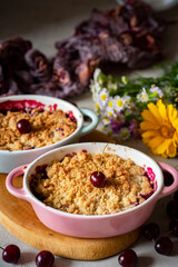 Cherry crumble in a white plate on a gray background. Cherry pie. Close-up. Vertical photo