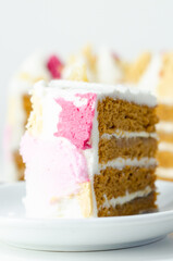A slice of cake with a pink,yellow and white frosting on top