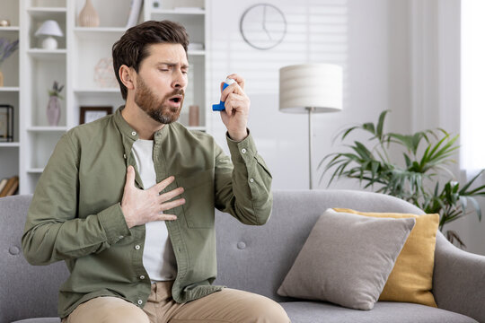 Man experiencing breathing difficulty while using asthma inhaler. Concept of respiratory health, asthma management, and home treatment. Depicts healthcare, emergency, medication, and personal care.