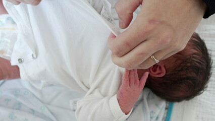 Mother Dressing Newborn - mother tenderly dressing her newborn son's hands, illustrating the loving relationship between mother and child in the early days