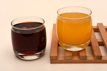 Juice in glass cups on a stand. Cherry and orange juice.
