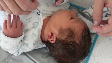 Mother's hands gently drying newborn baby hair and head with towel laid after bath