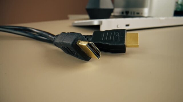 close-up on light beige table there is an HDMI cable for connecting the monitor power supply wired power